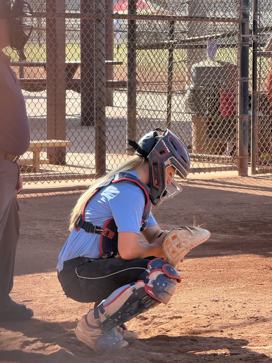 Softball catcher reading a pitch call on a wristband
